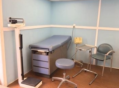 An examination room aboard Mercy, with an examination table, a floor scale and clinical instruments.