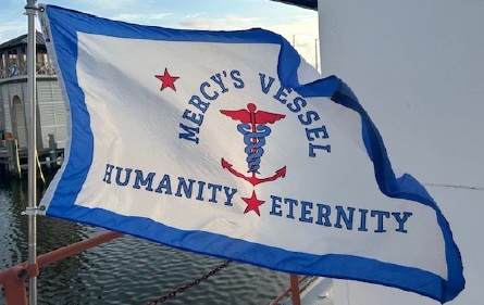 The vessel's flag: a caduceus crossed with an anchor above the words HUMANITY and ETERNITY.
