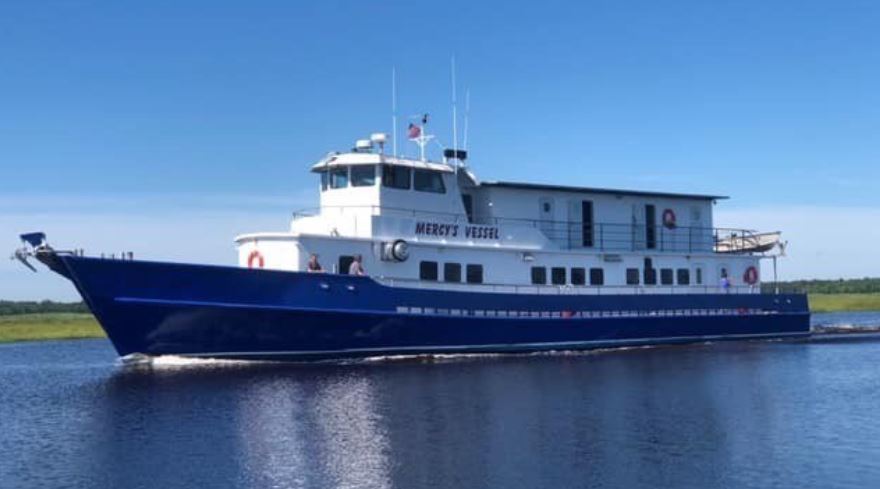 The mission vessel Mercy at rest on calm open water under a wide sky.